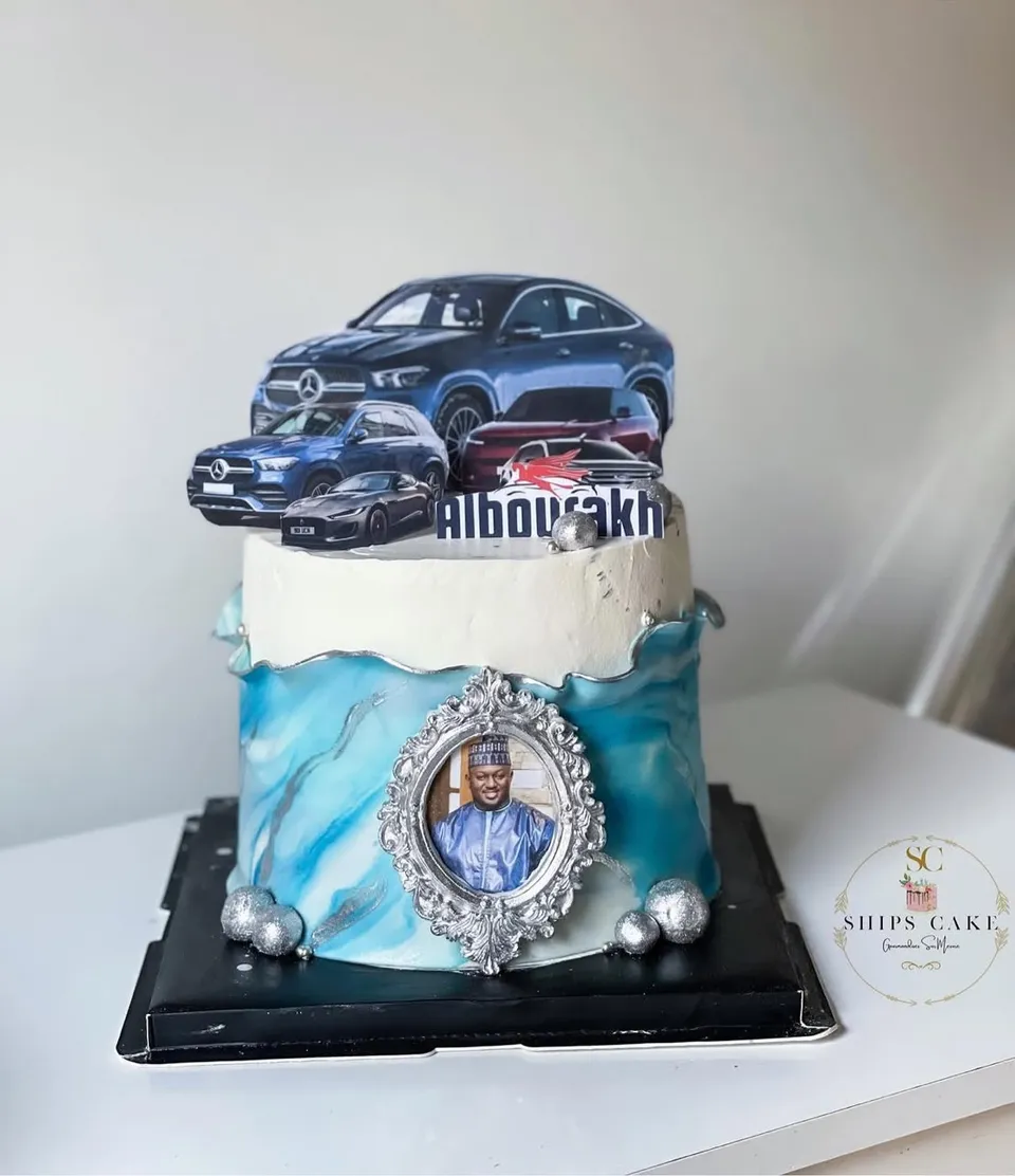 Gâteau bleu marbré décoré de voitures, avec un médaillon photo et des perles argentées