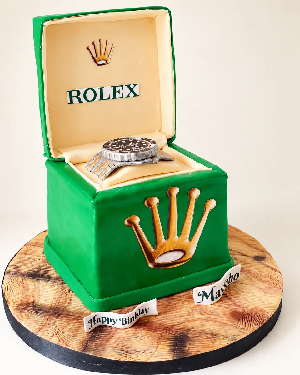 Gâteau sculpté en forme d'écrin à montre vert, avec une montre en sucre