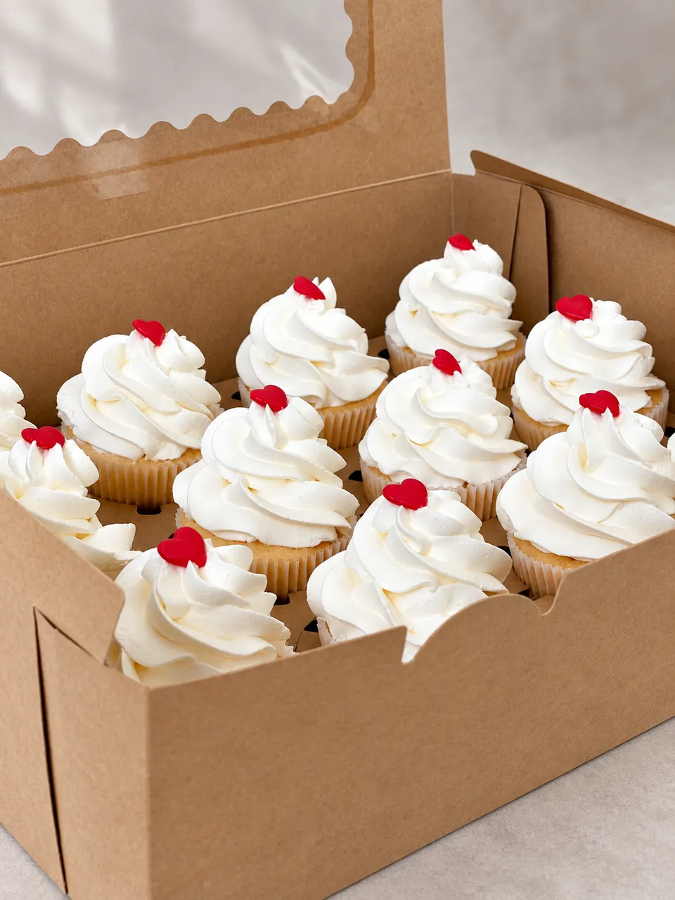 Boîte de douze cupcakes à la crème blanche, décorés d'un petit cœur rouge