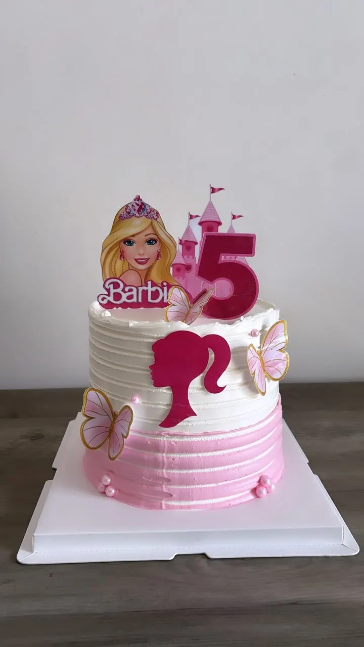 Gâteau d'anniversaire rose et blanc sur le thème Barbie, avec le chiffre 5 et des papillons