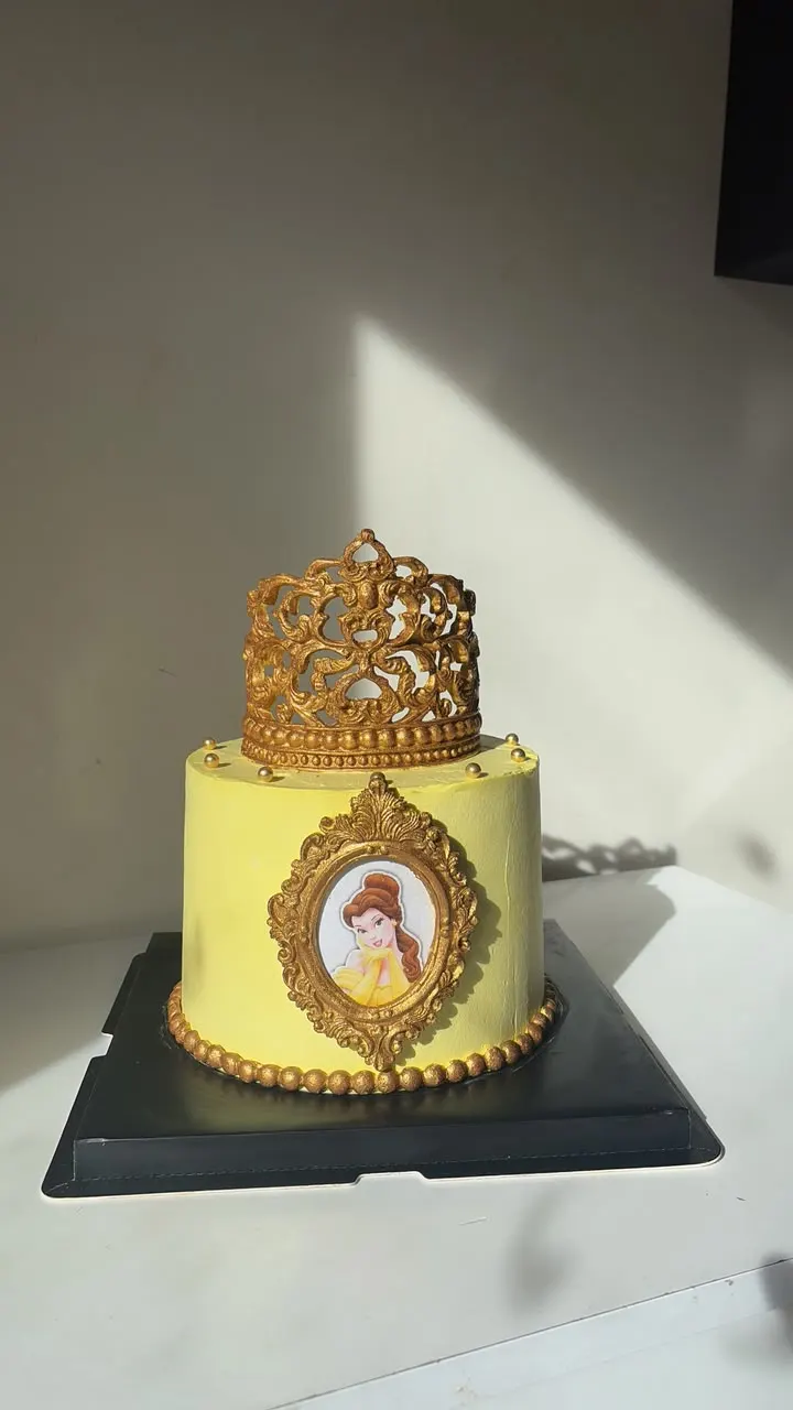 Gâteau jaune et or avec couronne et cadre doré autour d'une photo