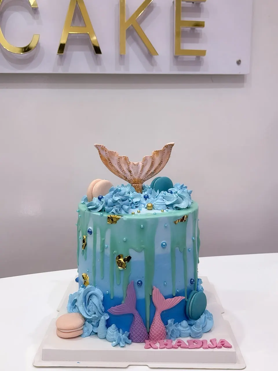 Gâteau sirène bleu et vert, queue dorée et coquillages en sucre