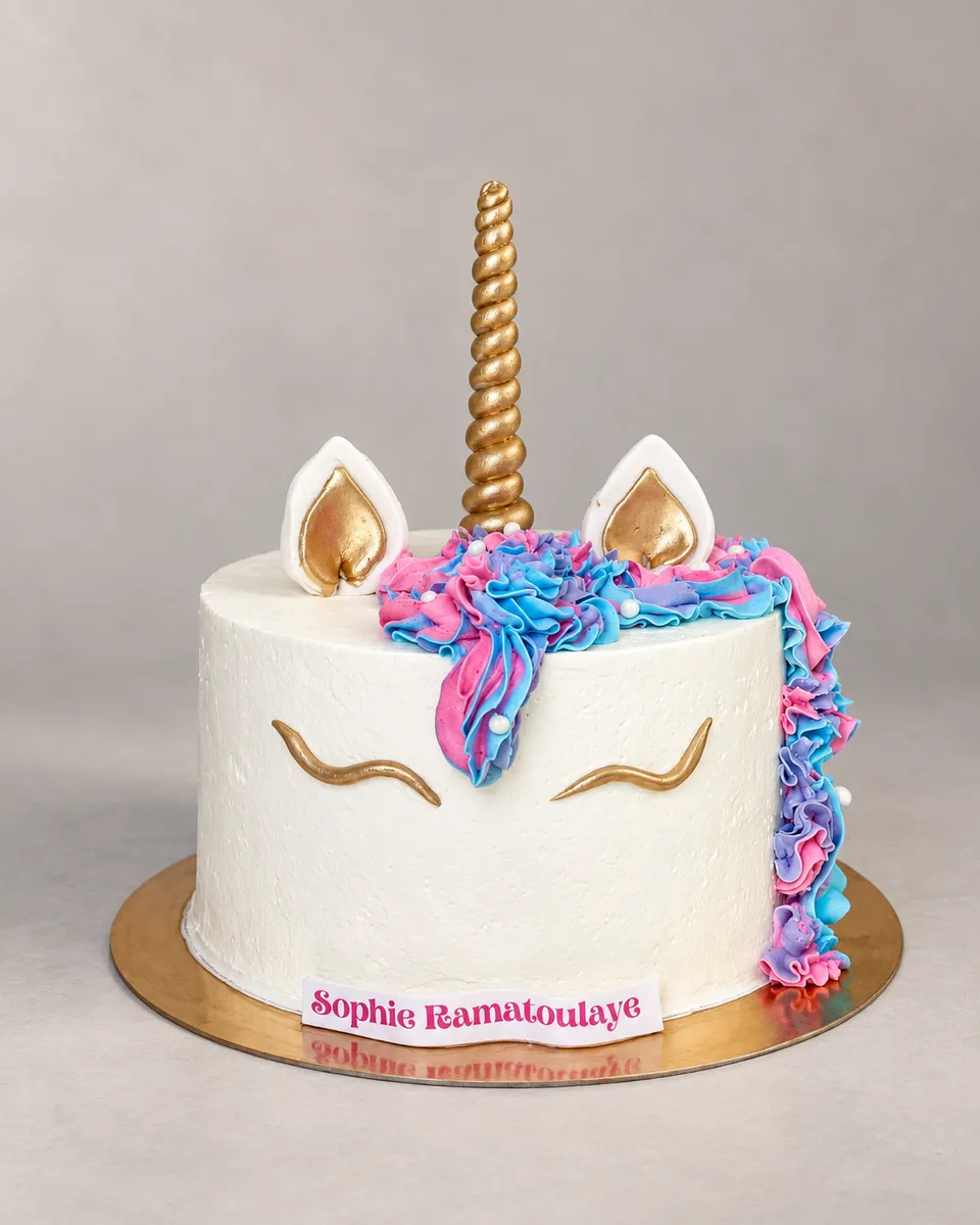 Gâteau licorne blanc, corne et oreilles dorées, crinière rose, bleue et mauve