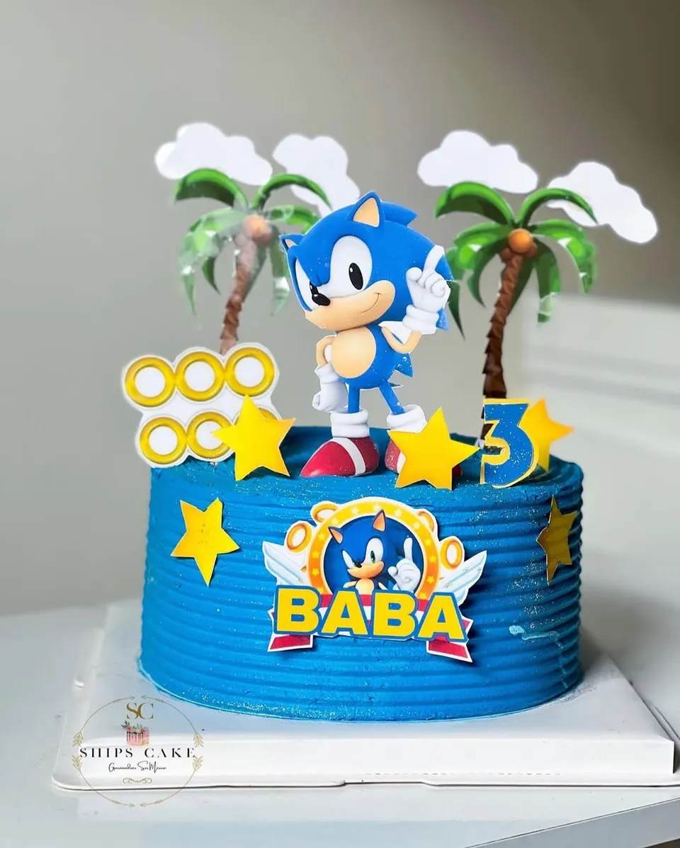 Gâteau bleu sur le thème Sonic, avec une figurine du personnage, des palmiers et des anneaux dorés