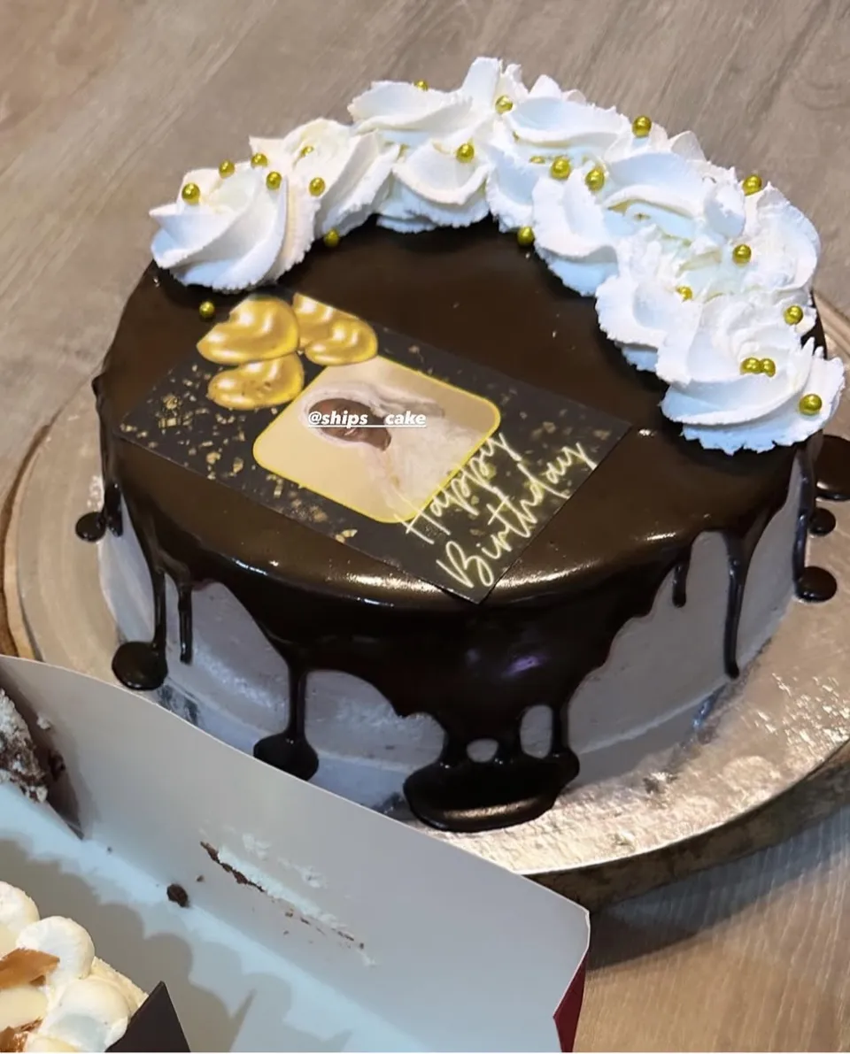 Gâteau nappé de ganache avec une couronne de chantilly et des perles dorées